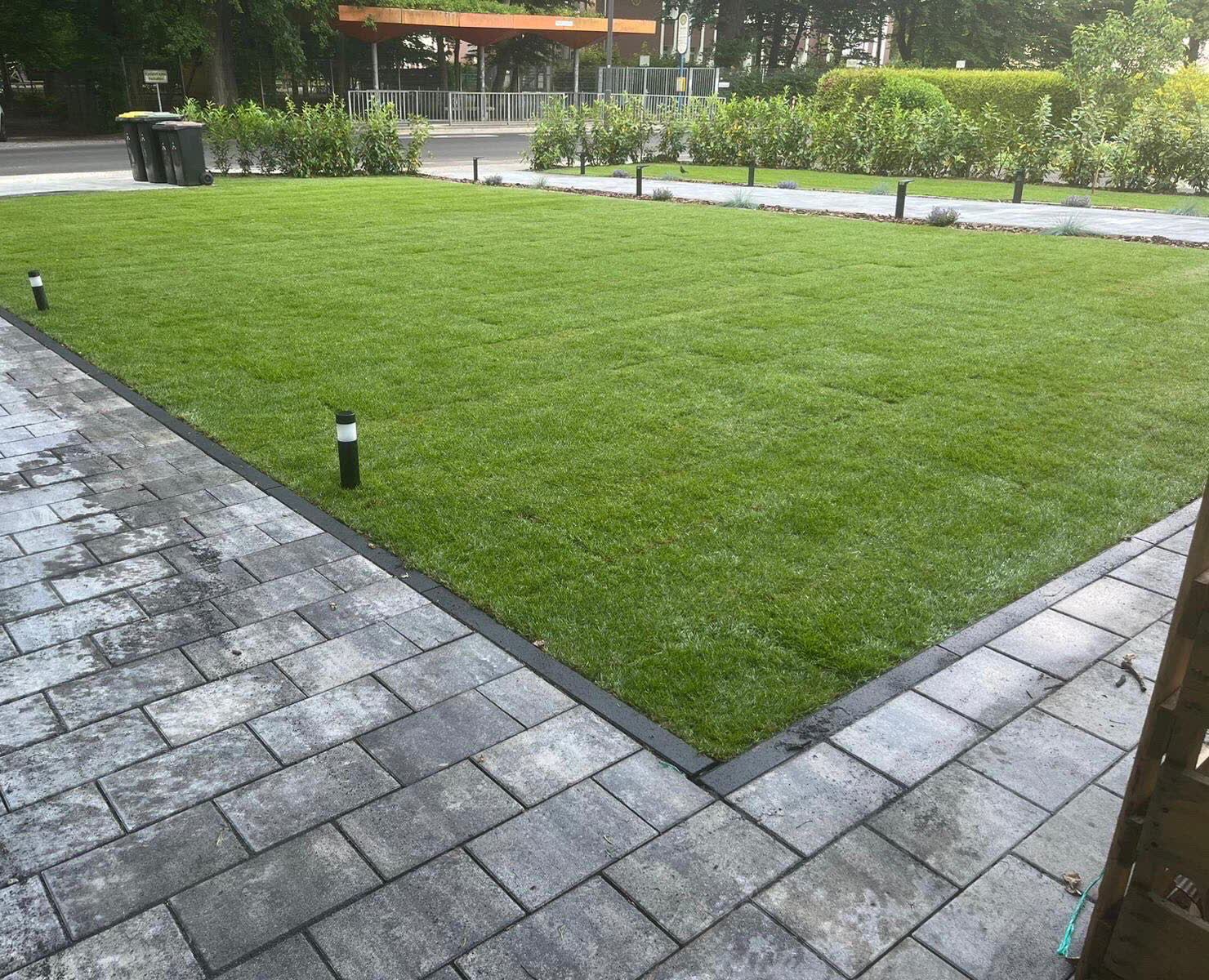 Frisch verlegter Rollrasen mit Pflasterflaeche und Gartenleuchten in Bonn